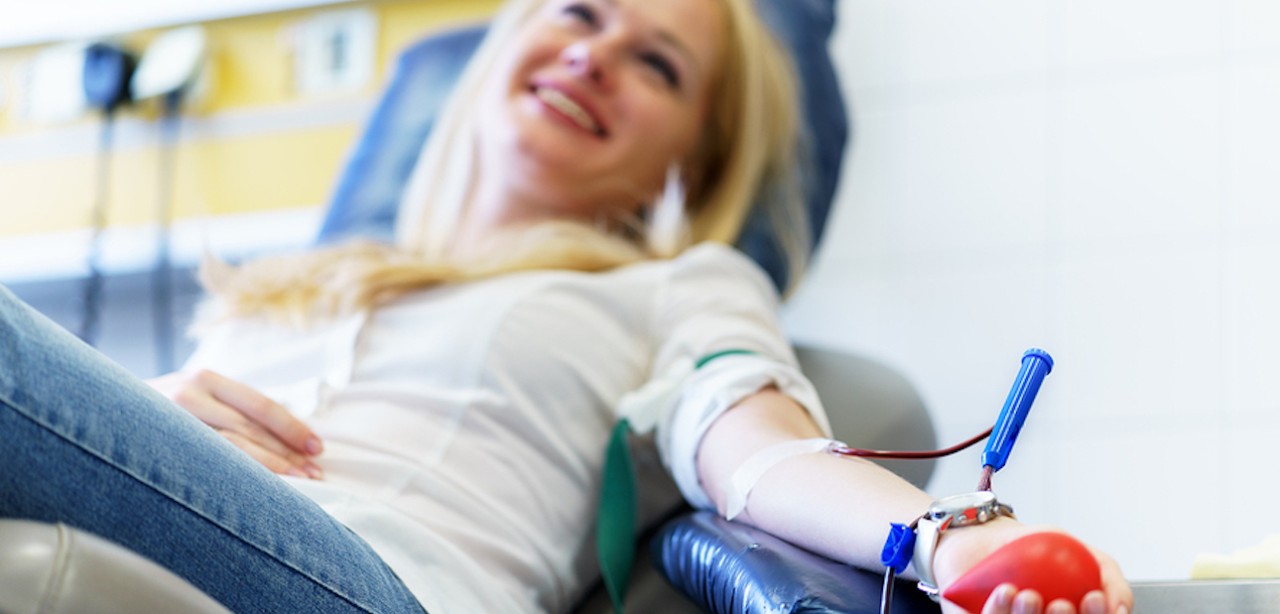 young caucasian woman with toy heart in the hand donates blood for saving lives and medical research in some hospital at day time