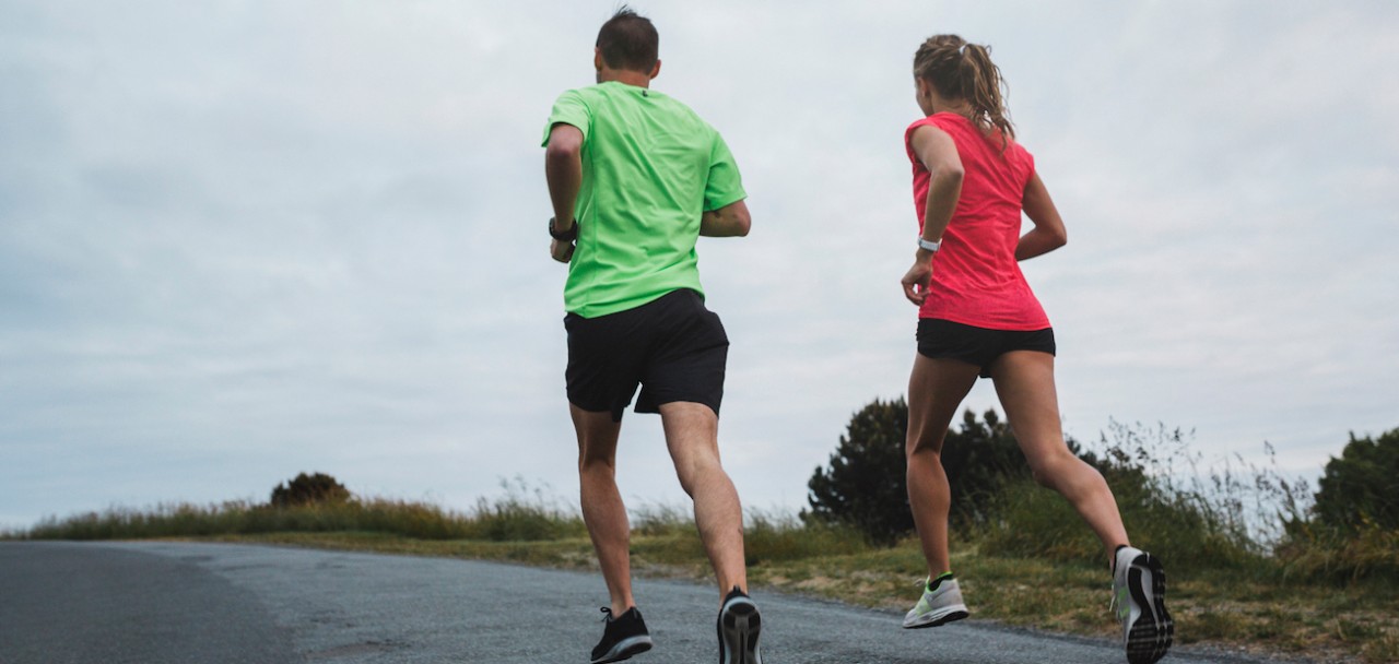 Motivated young couple running together outside on cold, windy day