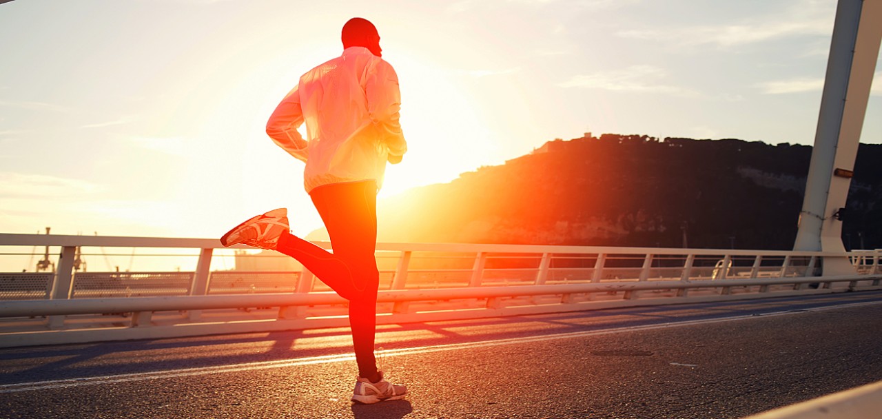 Attractive fit man running fast along big modern bridge at sunset light, black man doing workout outdoors, silhouette runner in windbreaker jogging over bridge road with amazing sunset on background; Shutterstock ID 234551020; PO: 123